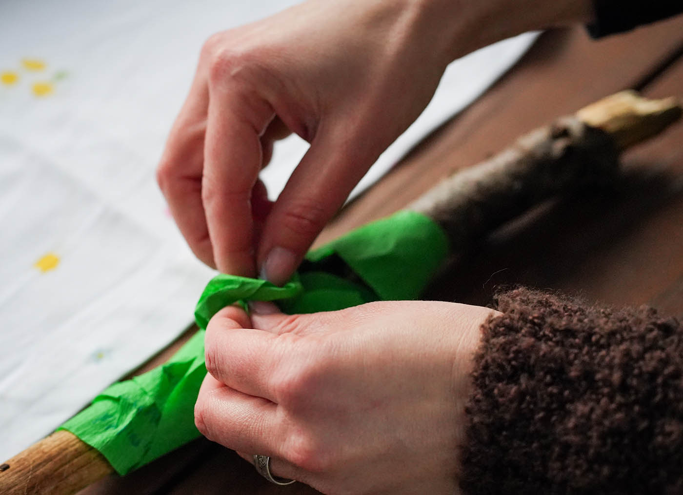 Teilnehmer bindet Wunschband an Stock beim Ostara Ritual